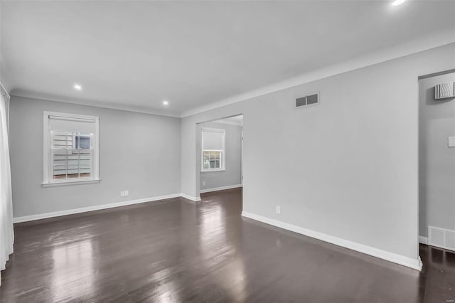 empty room featuring dark wood-type flooring and a healthy amount of sunlight