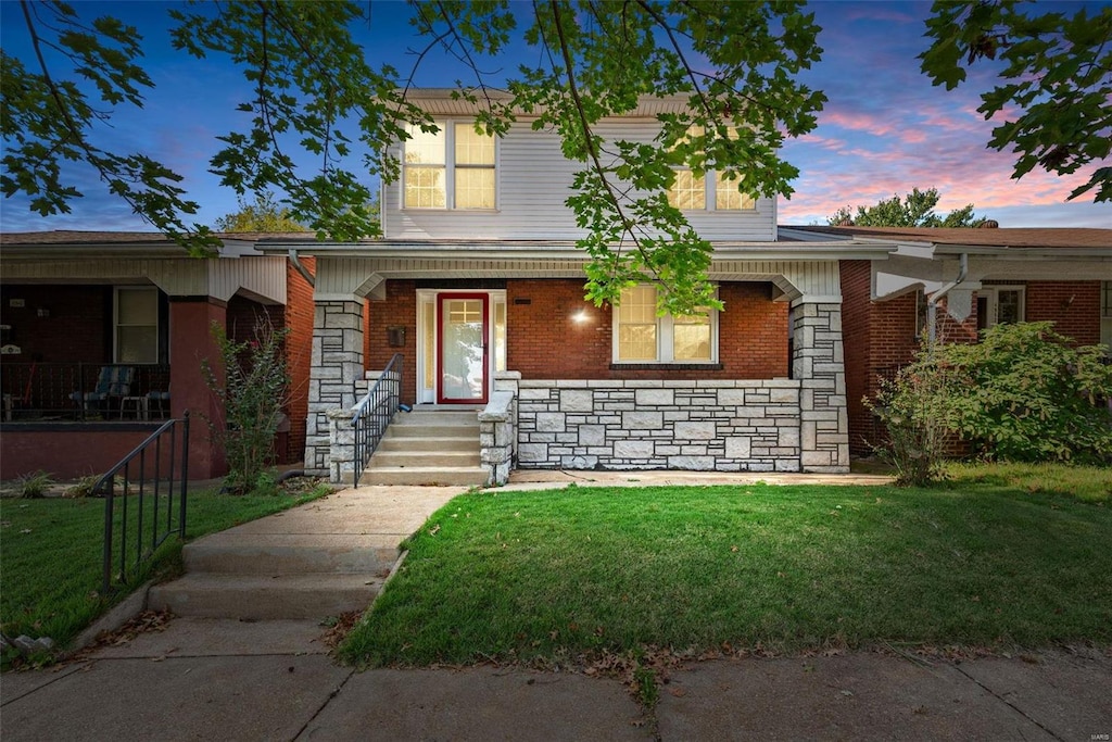 view of front of property with covered porch and a lawn