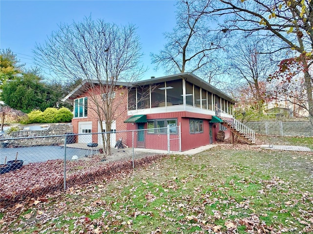 rear view of property featuring a sunroom and a yard