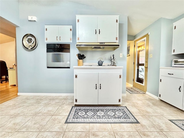 kitchen with stainless steel oven, white cabinets, and light tile patterned flooring