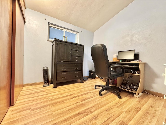 office space featuring vaulted ceiling and light hardwood / wood-style flooring