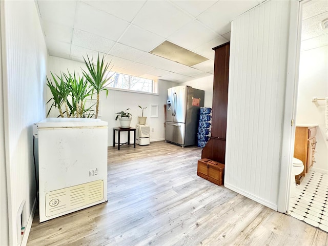 interior space with a drop ceiling and light hardwood / wood-style floors