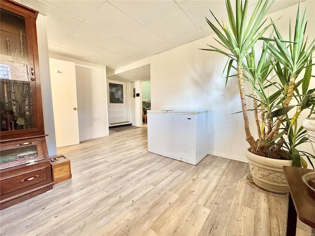 interior space with a drop ceiling and light wood-type flooring