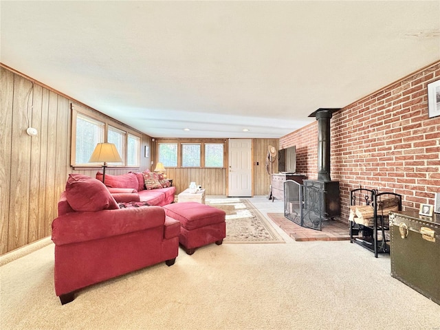 carpeted living room with a wood stove, wood walls, and brick wall