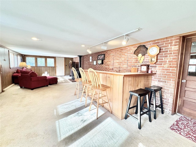 interior space with a kitchen breakfast bar, light carpet, and wood walls