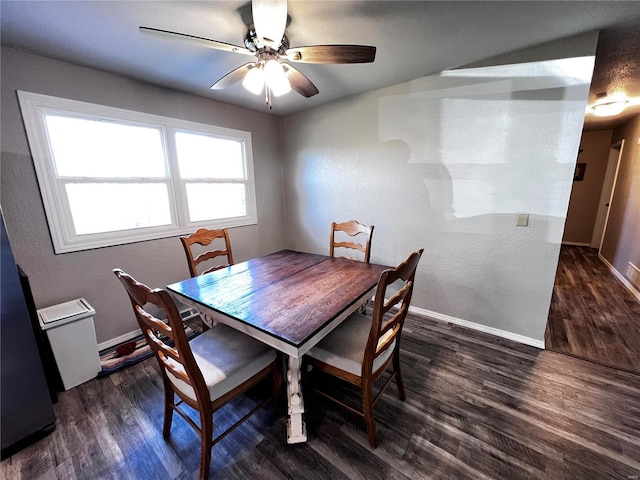 dining room featuring a ceiling fan, a textured wall, dark wood finished floors, and baseboards