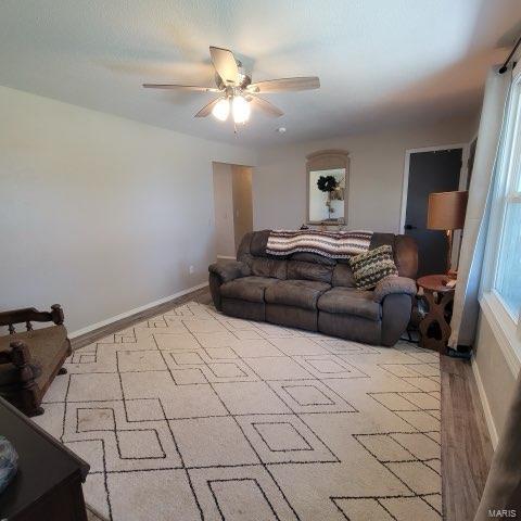 living area with ceiling fan and baseboards