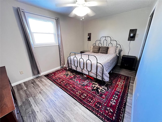 bedroom with a ceiling fan, baseboards, and wood finished floors