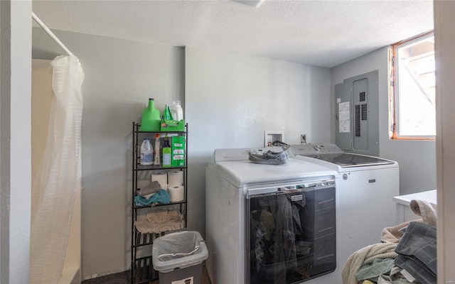 clothes washing area with washer and clothes dryer, electric panel, and a textured ceiling