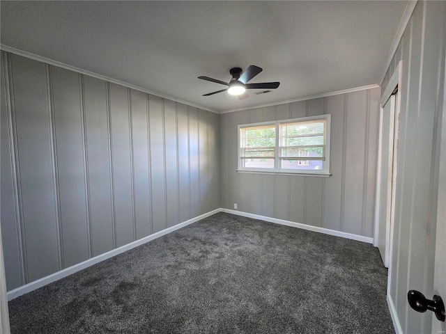 empty room featuring ceiling fan, crown molding, and dark colored carpet