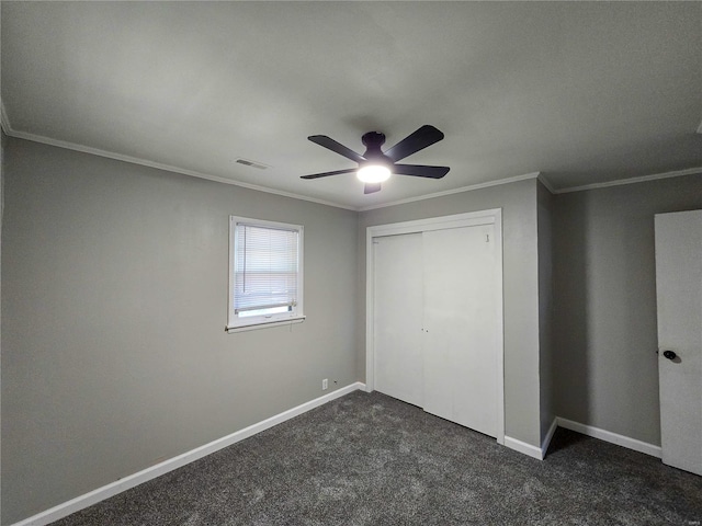 unfurnished bedroom with ceiling fan, a closet, dark carpet, and ornamental molding