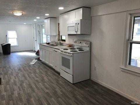 kitchen with white appliances, sink, dark hardwood / wood-style floors, and white cabinets