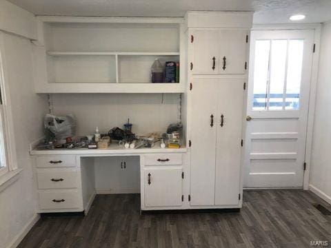 bar featuring white cabinets, built in desk, and dark hardwood / wood-style flooring