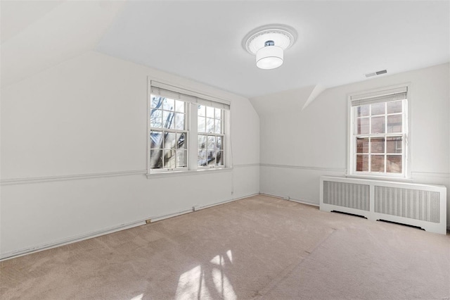 bonus room featuring light colored carpet, radiator heating unit, and vaulted ceiling