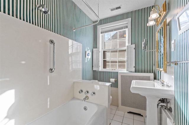 bathroom featuring toilet, tile patterned flooring, a textured ceiling, and a bath