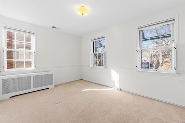 empty room featuring radiator and light carpet