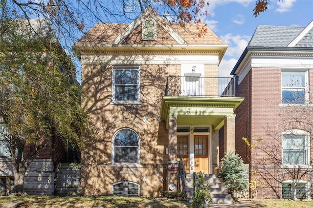 view of front facade featuring brick siding and a balcony