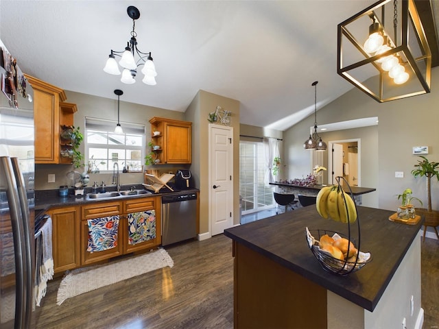 kitchen with appliances with stainless steel finishes, vaulted ceiling, dark wood-type flooring, sink, and a center island