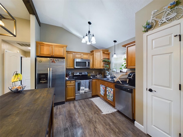 kitchen with sink, pendant lighting, vaulted ceiling, dark hardwood / wood-style flooring, and stainless steel appliances