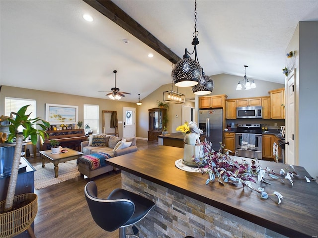 kitchen featuring appliances with stainless steel finishes, ceiling fan with notable chandelier, decorative light fixtures, vaulted ceiling with beams, and dark hardwood / wood-style floors