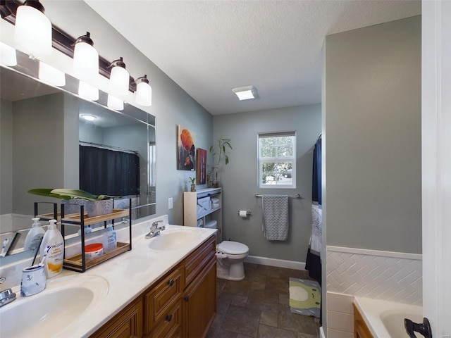 bathroom with a bathing tub, vanity, a textured ceiling, and toilet