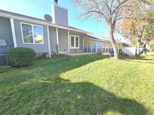 rear view of property featuring a lawn, a patio area, and central AC