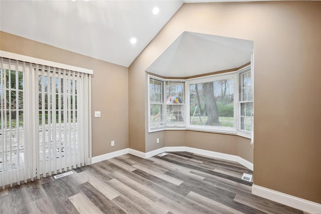 spare room featuring hardwood / wood-style floors and vaulted ceiling