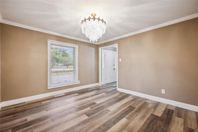 unfurnished dining area with hardwood / wood-style floors, crown molding, and an inviting chandelier