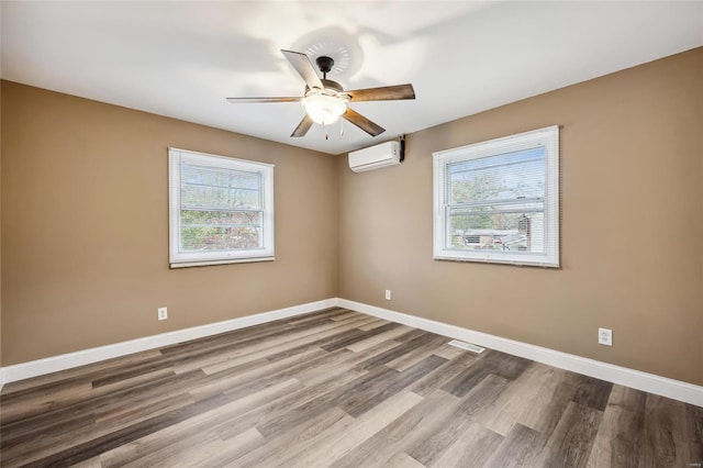 spare room featuring a wall mounted air conditioner, ceiling fan, and hardwood / wood-style floors