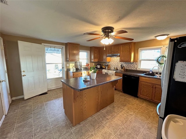 kitchen with ceiling fan, a center island, sink, decorative backsplash, and appliances with stainless steel finishes