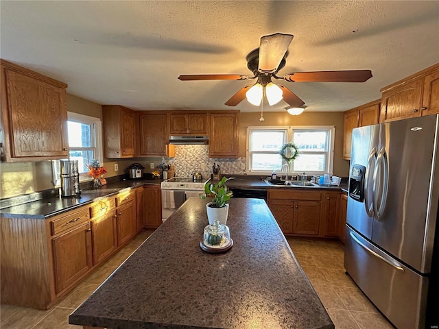 kitchen featuring appliances with stainless steel finishes, backsplash, ceiling fan, sink, and a center island