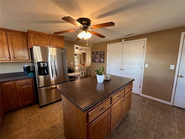 kitchen with stainless steel fridge, a center island, a textured ceiling, and ceiling fan