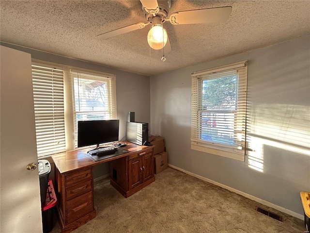 carpeted office featuring ceiling fan, plenty of natural light, and a textured ceiling