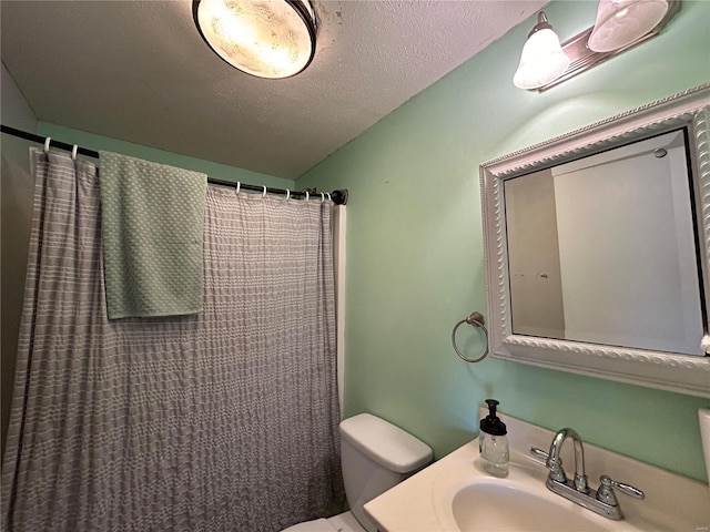 bathroom with toilet, sink, a textured ceiling, and walk in shower