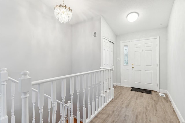 foyer entrance featuring light hardwood / wood-style flooring and a notable chandelier