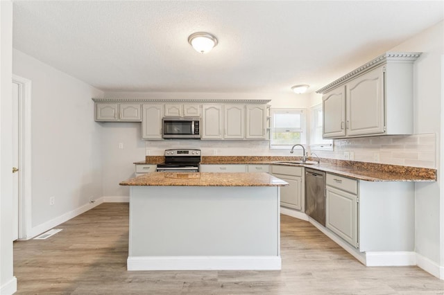 kitchen featuring gray cabinetry, a center island, sink, light hardwood / wood-style floors, and stainless steel appliances