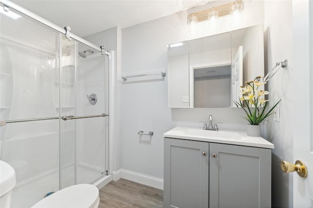 bathroom with hardwood / wood-style floors, vanity, toilet, and an enclosed shower