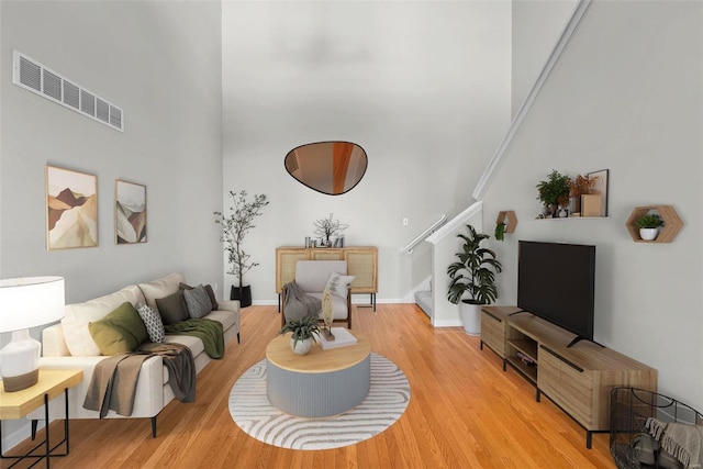 living room with light hardwood / wood-style floors and a high ceiling