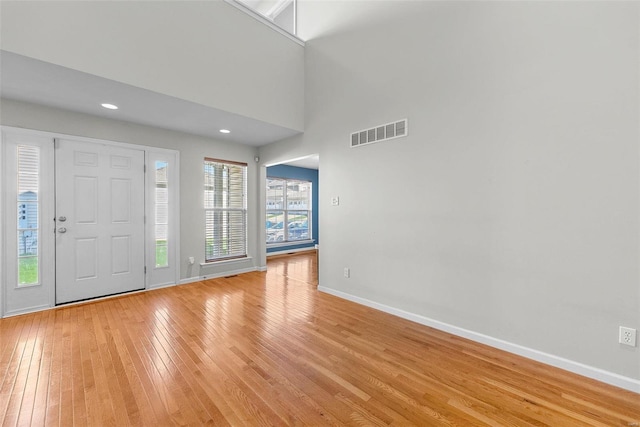 foyer entrance with light wood-type flooring and a high ceiling