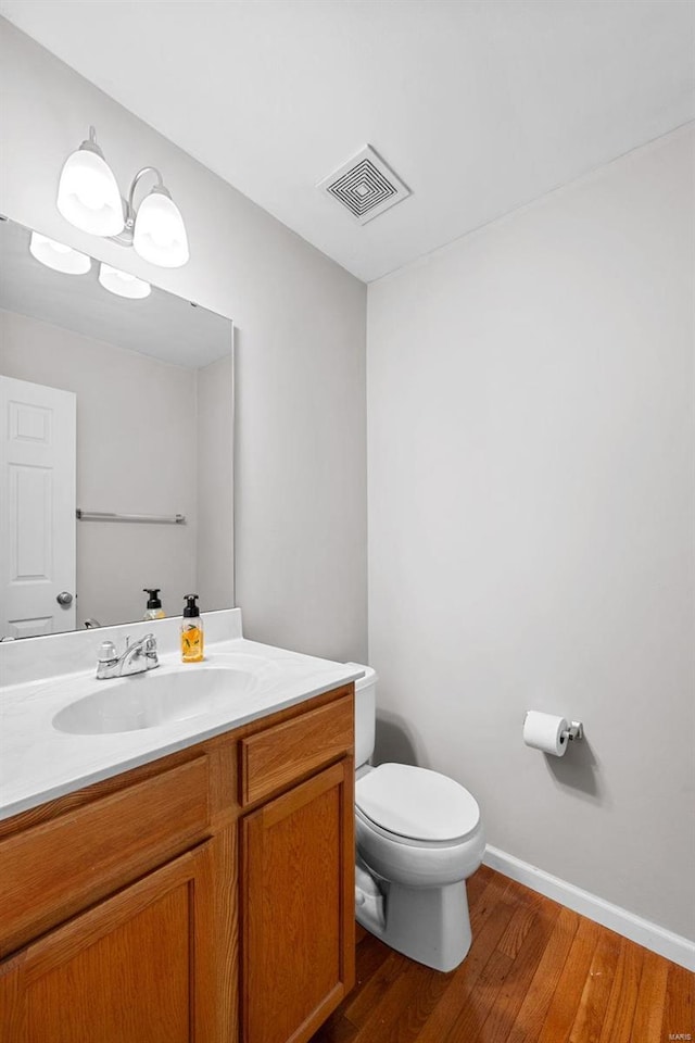 bathroom with hardwood / wood-style floors, vanity, and toilet