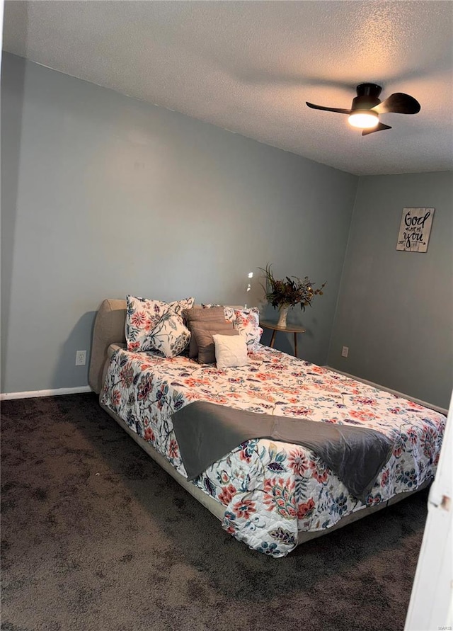 bedroom featuring dark colored carpet, a textured ceiling, and ceiling fan