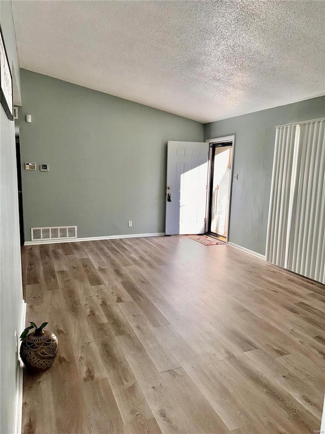 unfurnished room with light hardwood / wood-style flooring and a textured ceiling