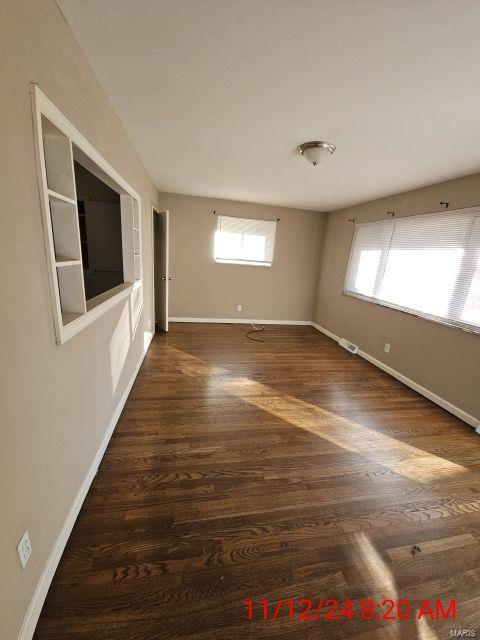 spare room with a healthy amount of sunlight, baseboards, and wood finished floors