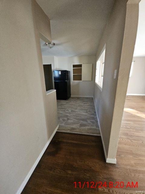 corridor with wood finished floors, baseboards, and a textured ceiling