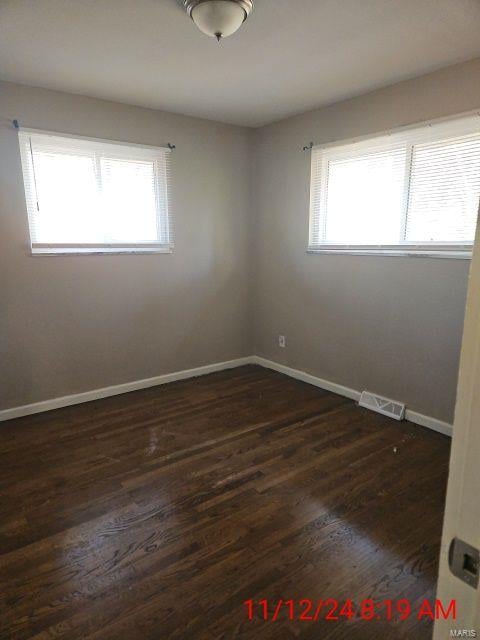 spare room featuring plenty of natural light and dark hardwood / wood-style flooring