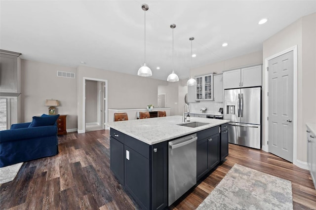 kitchen featuring pendant lighting, white cabinetry, sink, a kitchen island with sink, and stainless steel appliances