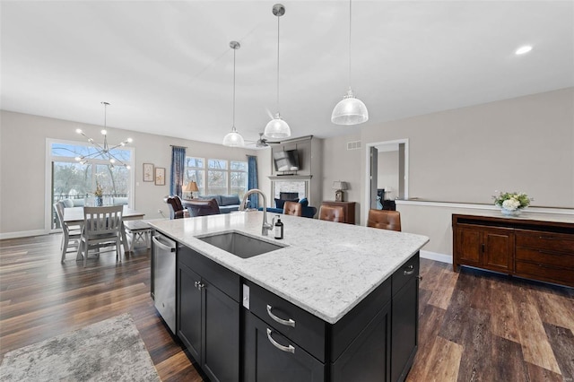 kitchen featuring hanging light fixtures, a kitchen island with sink, sink, and dark wood-type flooring