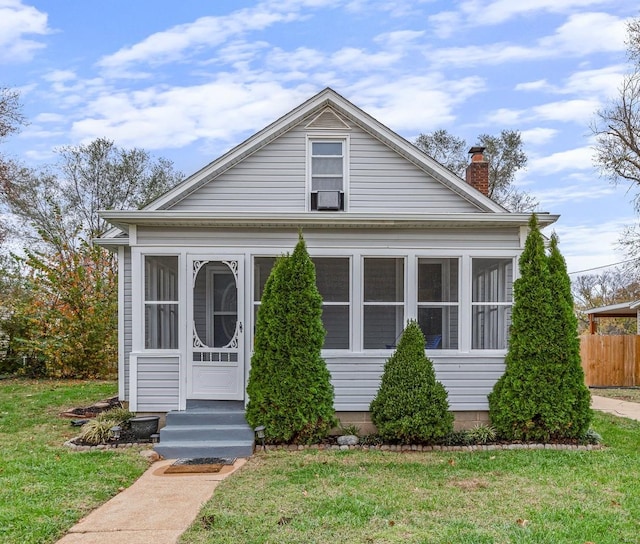 neoclassical / greek revival house with cooling unit, a sunroom, and a front lawn