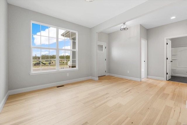 empty room with baseboards, light wood finished floors, visible vents, and recessed lighting