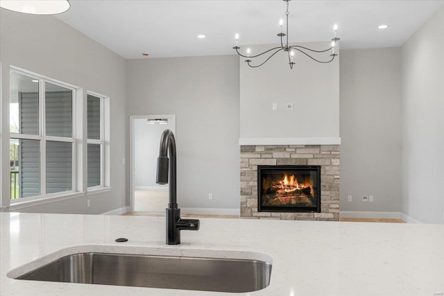 room details with an inviting chandelier, a fireplace, a sink, and recessed lighting